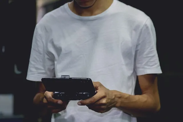 Mand i hvid t-shirt, der spiller på et håndholdt device